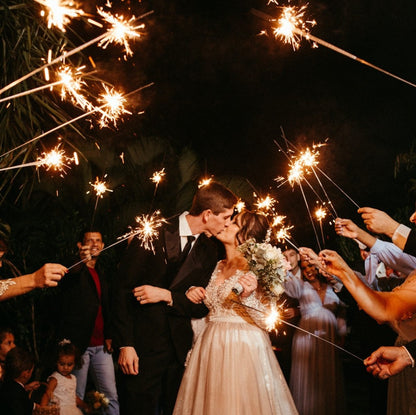 bride and groom kissing while guest hold wedding sparklers