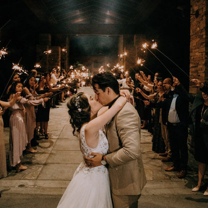 bride and groom kissing while wedding guest hold up wedding sparklers