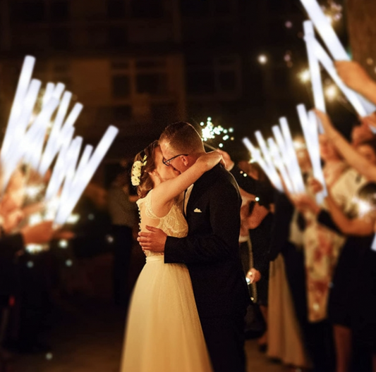 bride and groom kissing under LED white batons